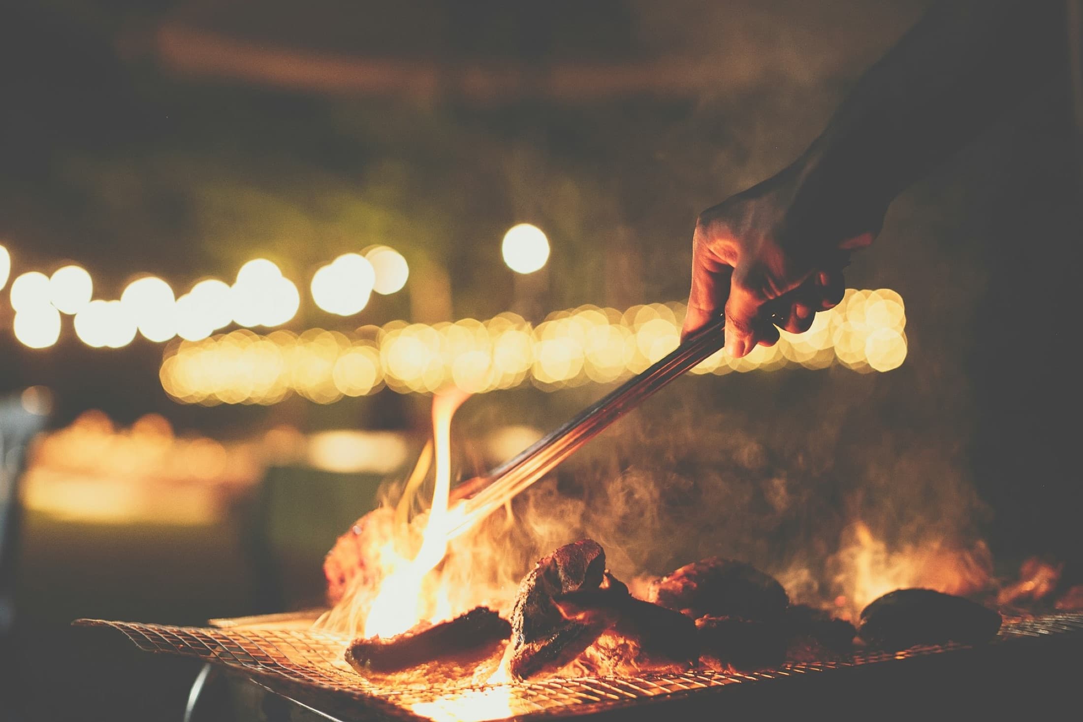 Plant-based sausages smoking over an open flame
